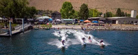 An aerial view of several people riding personal watercraft on a lake.