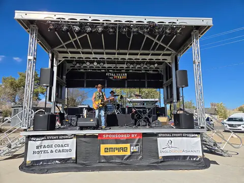 A band performs on an outdoor stage with sponsor banners displayed below.