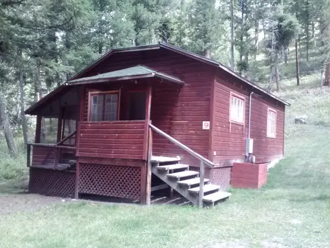 A red wooden cabin sits among trees.