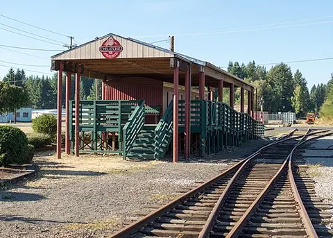 A covered railway platform with tracks in the foreground.