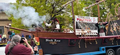 A parade float designed like a pirate ship with people in costume.