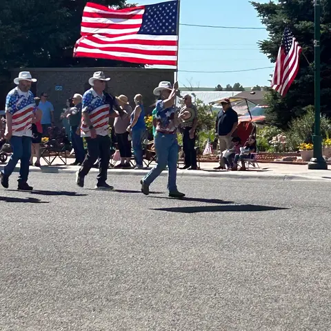 People carrying American flags in a parade outdoors.
