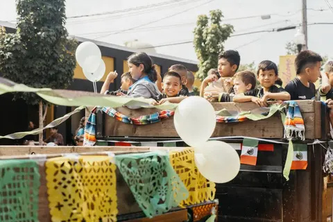 Children ride in a decorated truck bed during an outdoor event.