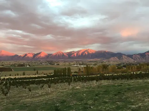 A sunset view over a valley with mountains in the background and fields in the foreground.