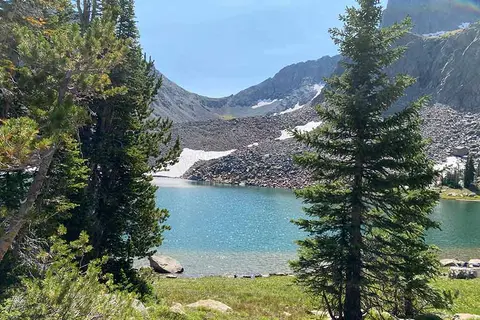 A scenic alpine lake framed by pine trees and rocky mountains.