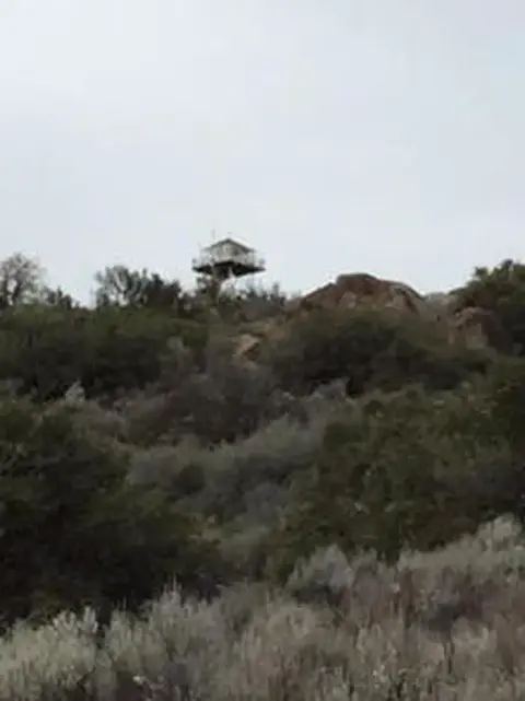 A small structure on a hilltop surrounded by vegetation.