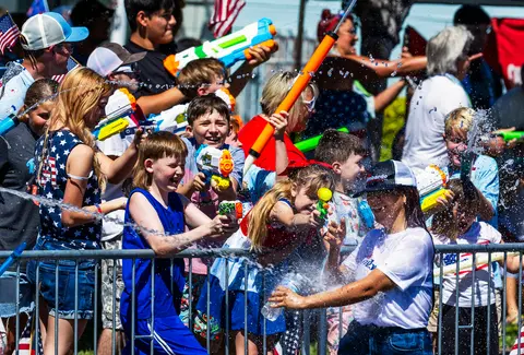 People playing with water guns behind a metal barrier.