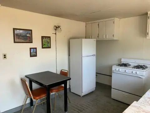 A small kitchen interior with a dining table, white refrigerator, and stove.