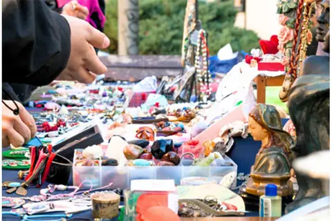 A street vendor displays various trinkets, jewelry, and figurines on a table.