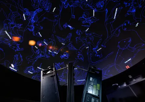 A planetarium projector displaying constellations on a dome ceiling.