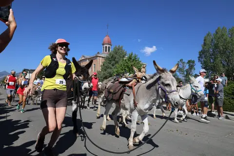 A woman running alongside a donkey in a street race event.