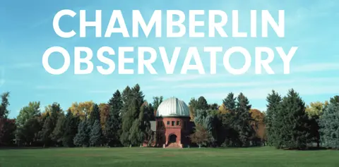 An exterior view of an observatory building surrounded by trees and a grassy lawn.