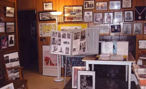 An interior room with wood paneling walls is covered in framed photographs and display stands.