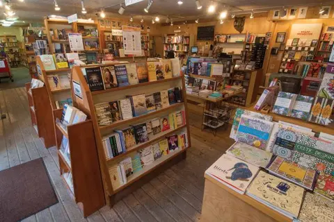 The interior of a bookstore filled with shelves and tables of books.