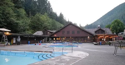 An outdoor swimming pool complex with multiple pools and a lodge building.