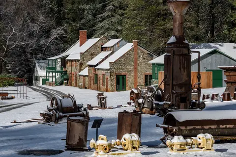 A historic stone and brick complex with old mining machinery dusted with snow.