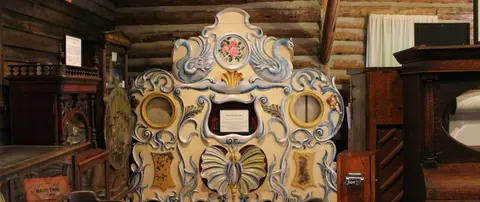 An ornate, hand-carved fairground organ inside a wooden room.