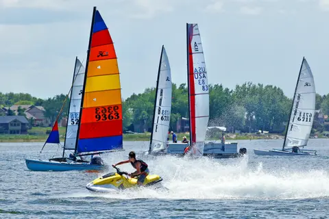 Sailboats and a jet ski on a lake.