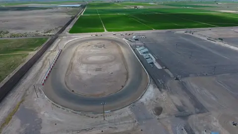 An aerial view of a dirt racetrack surrounded by farmland.