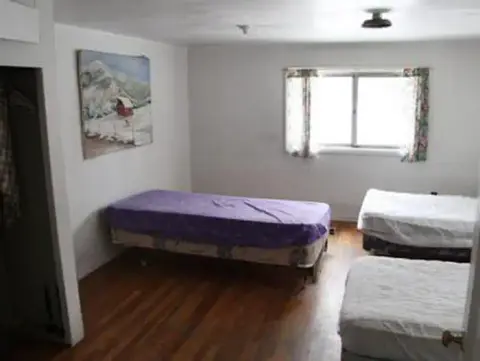 A bedroom with multiple beds and a painting on the wall.