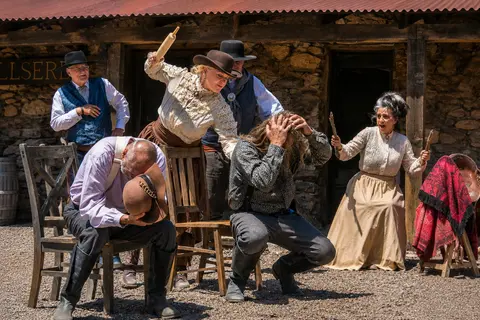 A costumed group acting out a humorous Western scene with people reacting playfully outdoors.