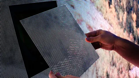 A person's hands holding up a section of an LED screen panel.