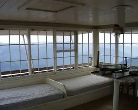 The interior of a fire lookout tower with windows looking out over mountains.
