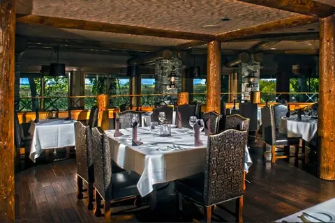 An interior view of a rustic restaurant dining room with set tables and wooden pillars.