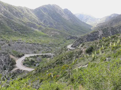 A winding road snakes through a mountainous valley with green slopes.