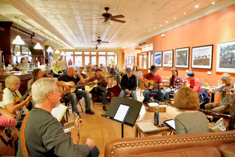 A group of people playing guitars and other instruments in an interior space.