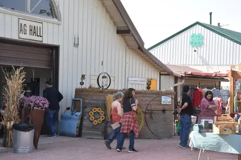 People walking near a building labeled AG Hall at an outdoor market.