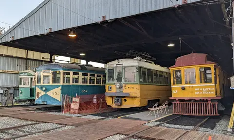 A row of historic streetcars parked inside a shed.