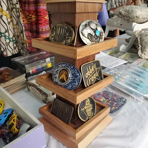 A wooden display stand holds various belt buckles on a table.