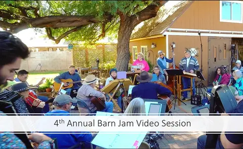 A group of people playing music outdoors by a barn.