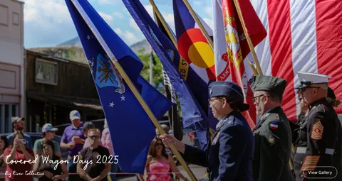 People in uniform carrying flags in a parade.
