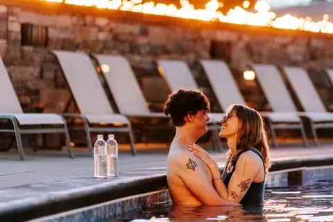 A couple embraces in a swimming pool at night.