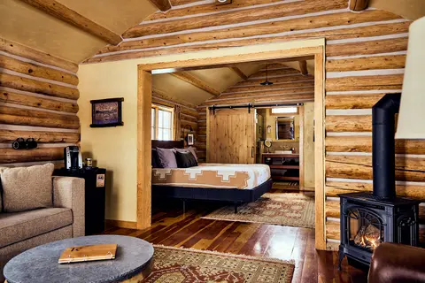 Interior view of a rustic log cabin living room and bedroom.