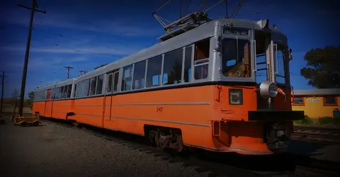A vintage orange and silver streetcar is parked on rails outside.