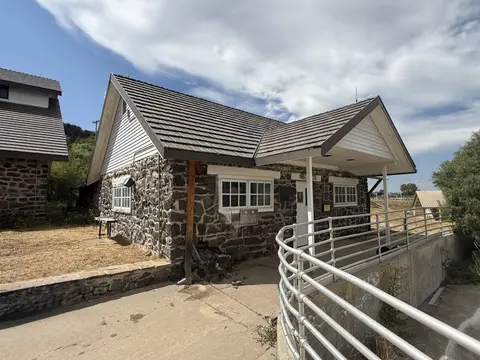 Exterior view of a historic stone building with a metal roof and a ramp.