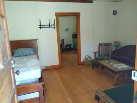 An interior view of a room with a bed, wooden furniture, and a doorway leading to another room.