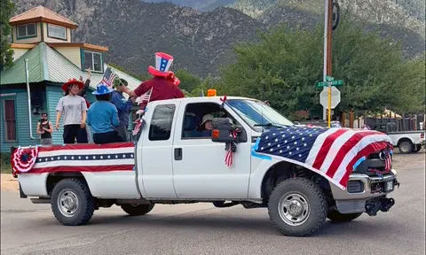 People ride in the back of a decorated truck during a parade.