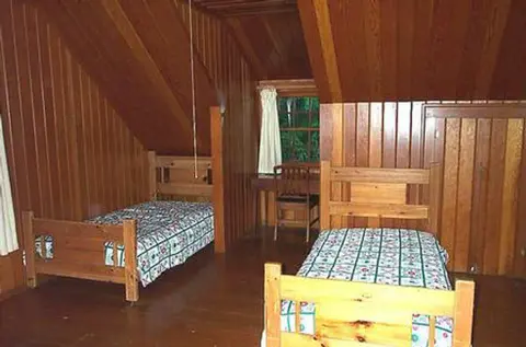 An interior shot of a wood-paneled bedroom with two single beds.