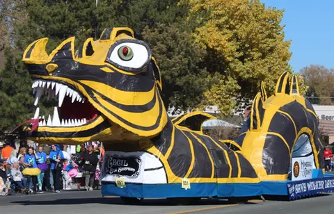 A large black and yellow sea serpent float moves down a street in a parade.