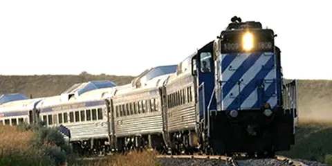 A passenger train travels along tracks through a landscape.