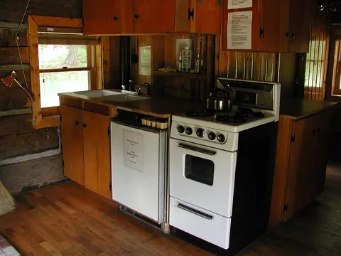 A rustic kitchen featuring wooden cabinets, a white stove, and a sink.