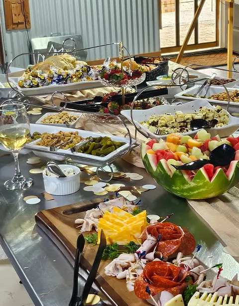 A buffet table loaded with a charcuterie board, fruit, cheeses, and snacks.