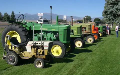 A line of vintage tractors parked on a grassy field.