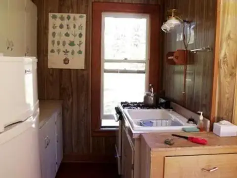 An interior view of a rustic kitchen with wood paneling and a small window.