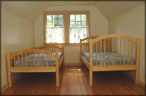 An attic bedroom with two wooden twin beds.