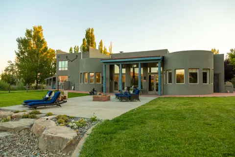 An exterior view of a modern house with a patio and lawn.